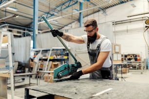 A worker using manual metal cutter for cutting metal parts.