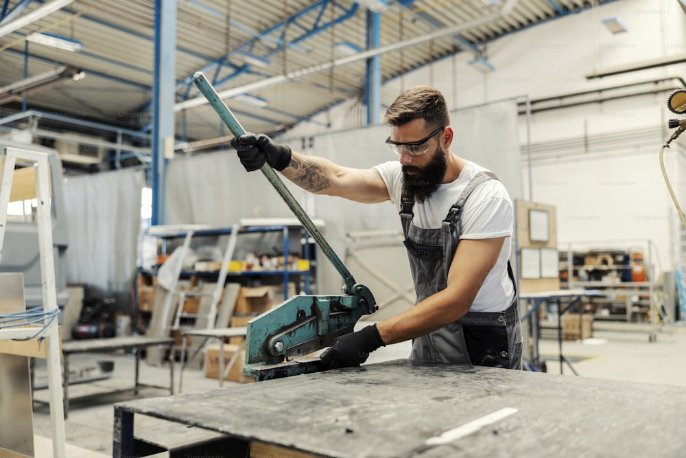 Un trabajador que utiliza un cortador de metal manual para cortar piezas metálicas.