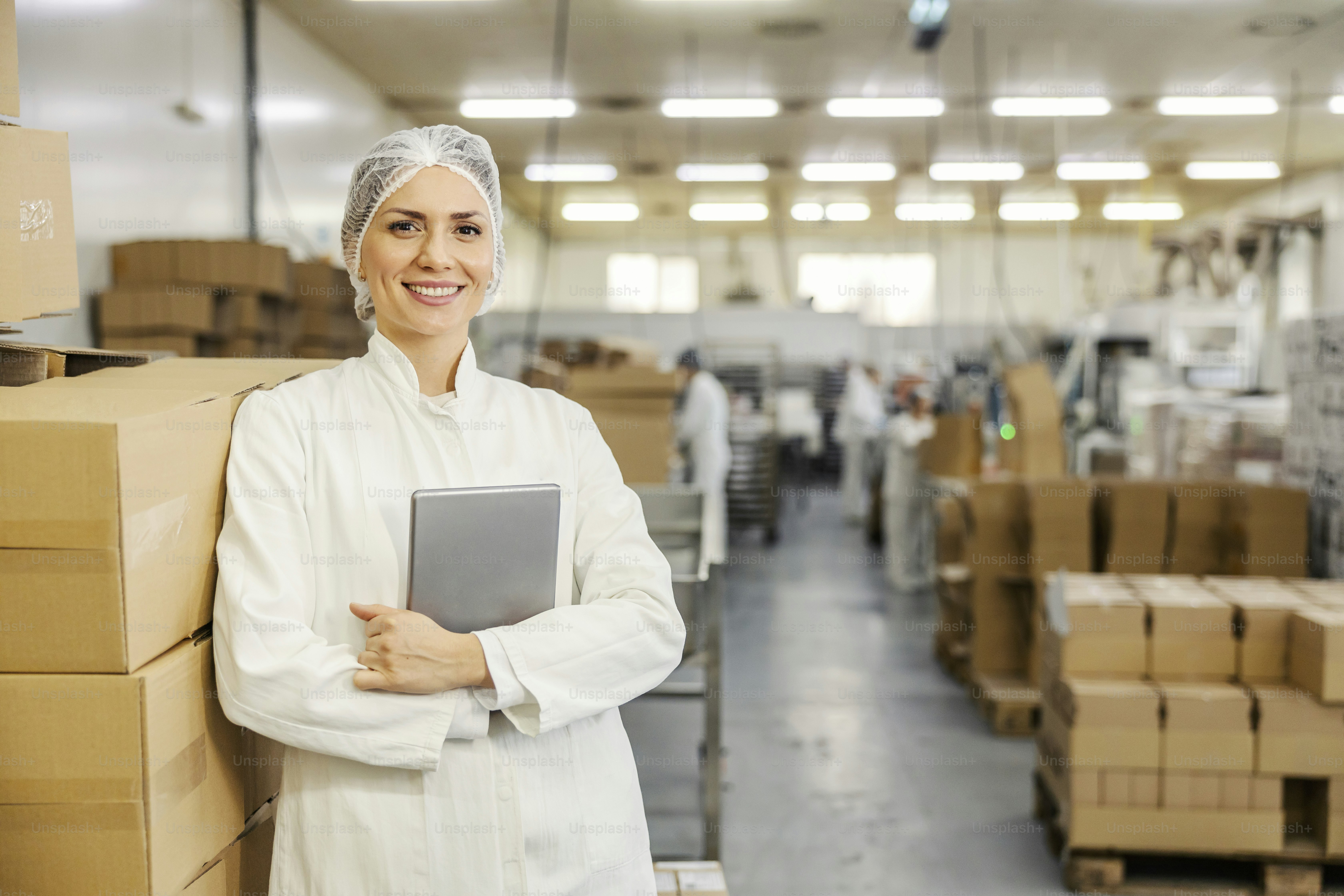 Portrait of food factory inspector leaning on boxes with merchandise ...