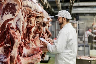 Un superviseur d’usine de viande évalue la qualité de la viande tout en utilisant des comprimés.