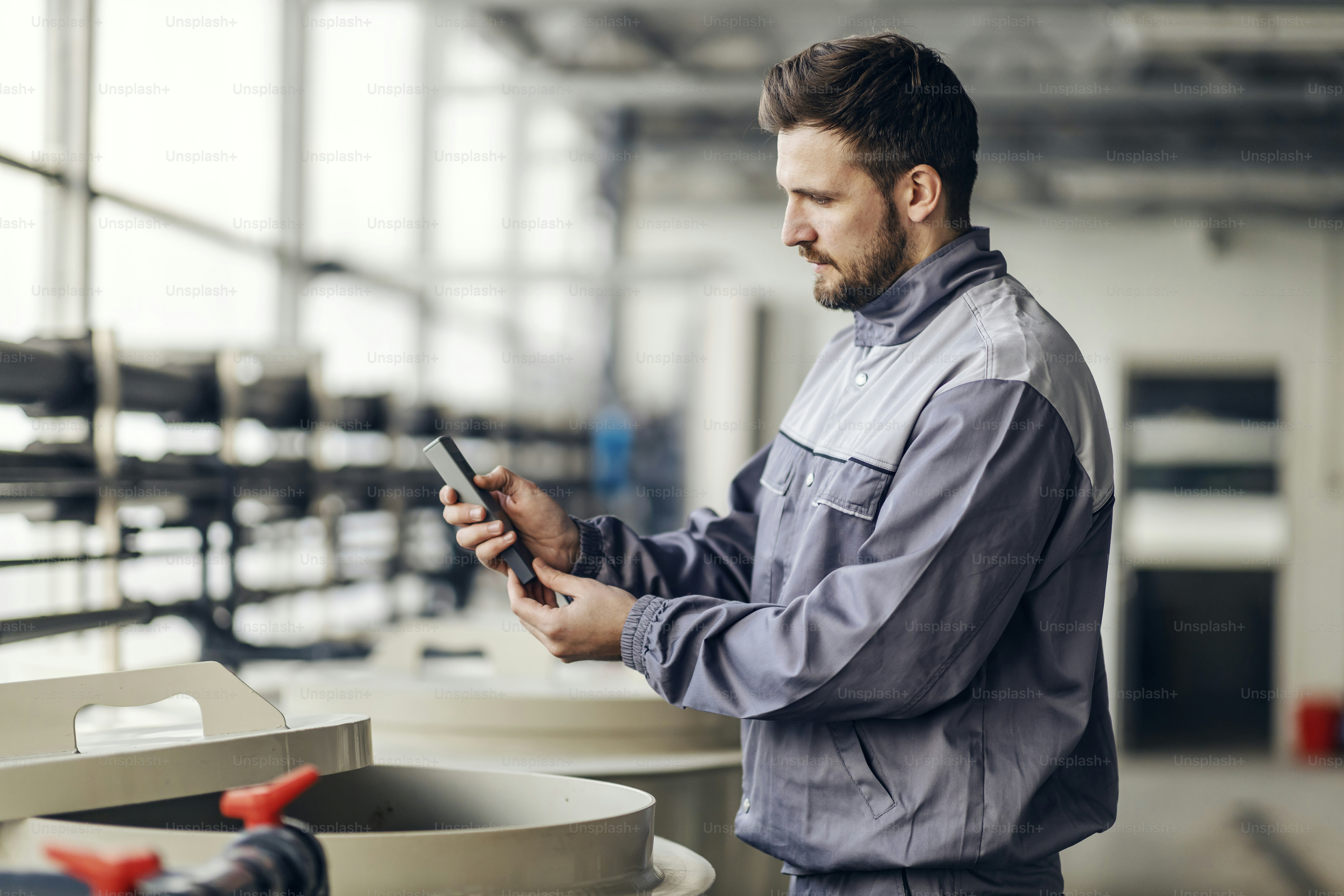 産業界の労働者は、コンテナの隣に立っている間、楽器を使って作業しています。