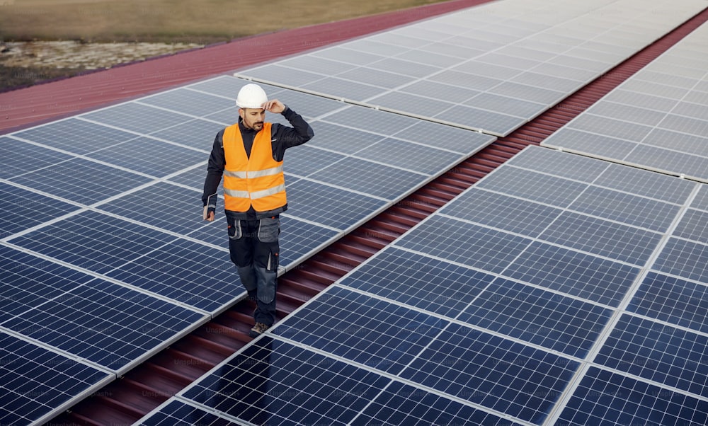 A handyman looking at solar panels on roof.