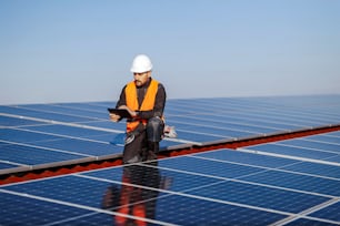 A inspector using tablet to check on solar panels on the roof.