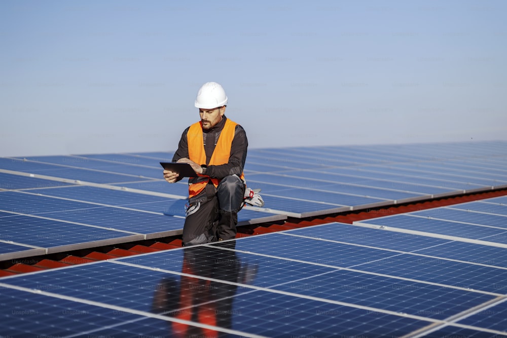 Un inspector usando una tableta para revisar los paneles solares en el techo.