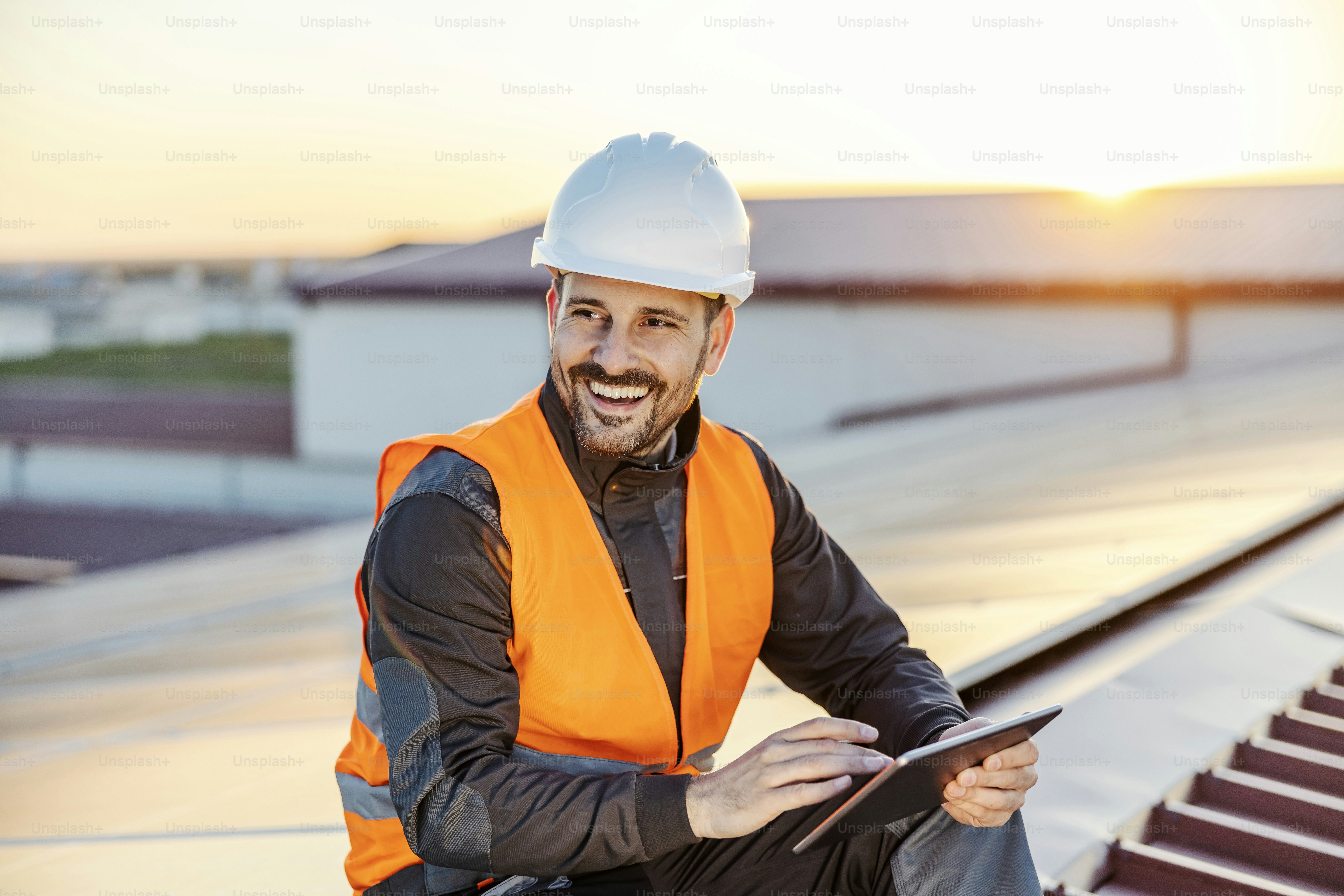 Un lavoratore sorridente che scorre su tablet sul tetto