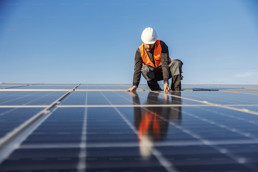 Ein Arbeiter, der Sonnenkollektoren auf dem Dach installiert.