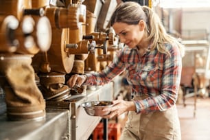 Um trabalhador de uma fábrica de café pegando café moído e medindo-o.