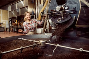 Eine Arbeiterin in einer Kaffeefabrik mit einer Kaffeeröstmaschine.