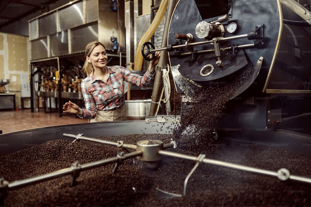 Una trabajadora de una fábrica de café usando una máquina tostadora de café.