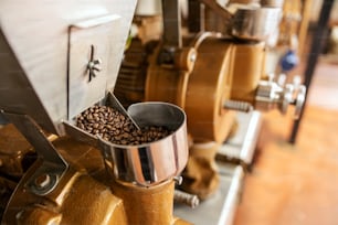 Close up da máquina de moagem de café com grãos de café na fábrica.