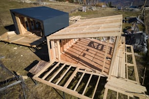 Luftaufnahme eines Holzrahmenhauses auf Pfahlgründung im Bau in den Bergen.