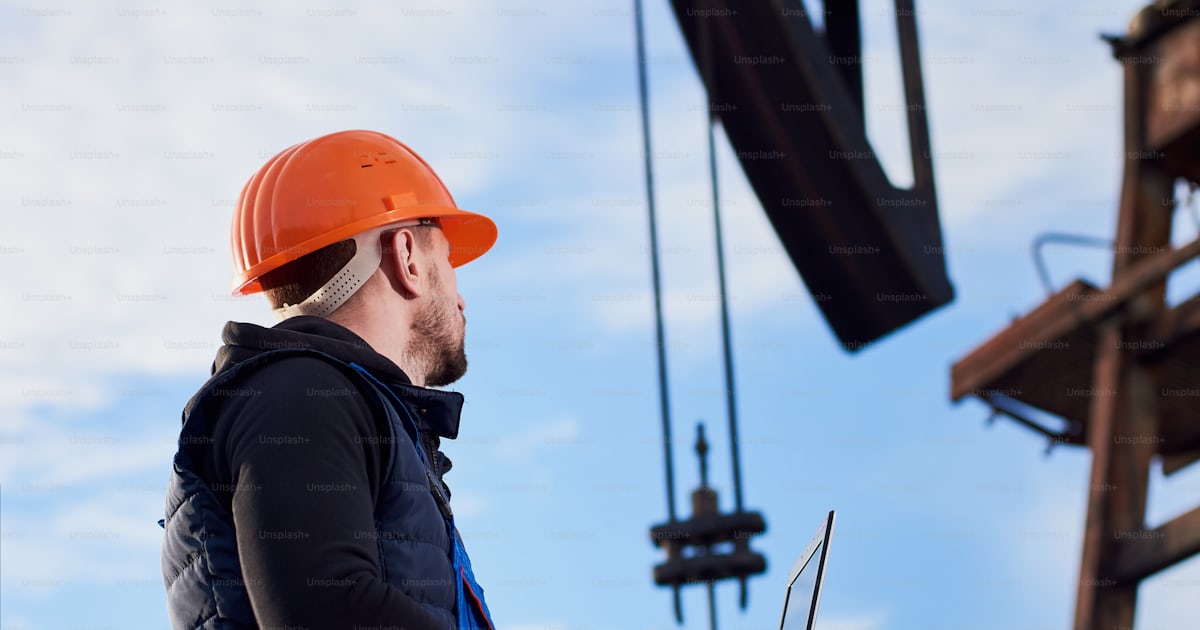 Oil man holding notebook and looking at oil pump rocker-machine. Male ...