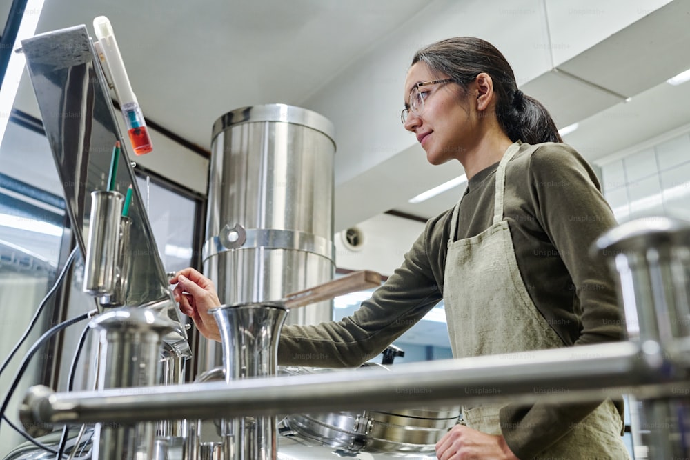 Trabajadora que controla el proceso de trabajo de los equipos durante su trabajo en el taller de la cervecería