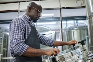 Ingegnere afroamericano concentrandosi sul suo lavoro, controllando le attrezzature a brewey