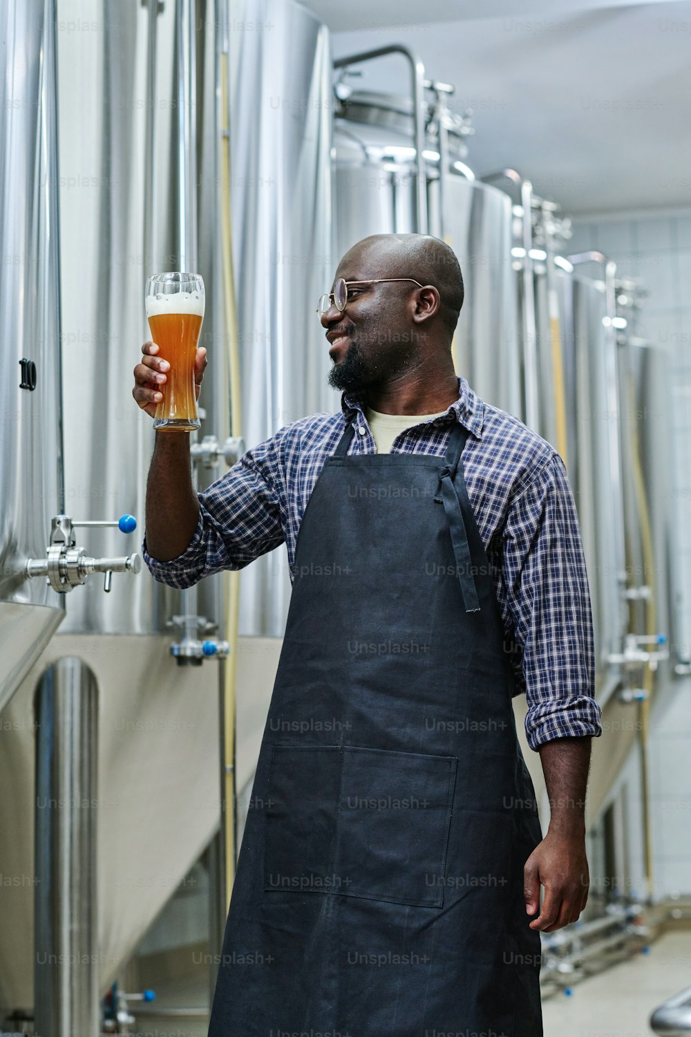 アフリカ系アメリカ人エンジニアがビール広告のグラスを笑顔で持ち、飲み物の質に満足している