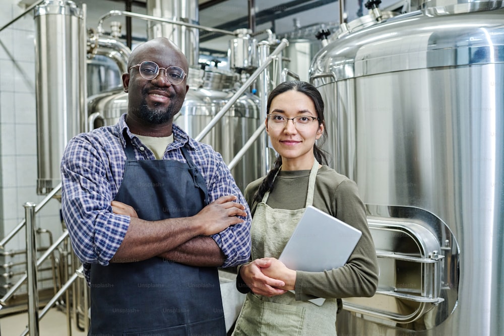 Portrait of couple of engineers looking at camera while working together at brewery