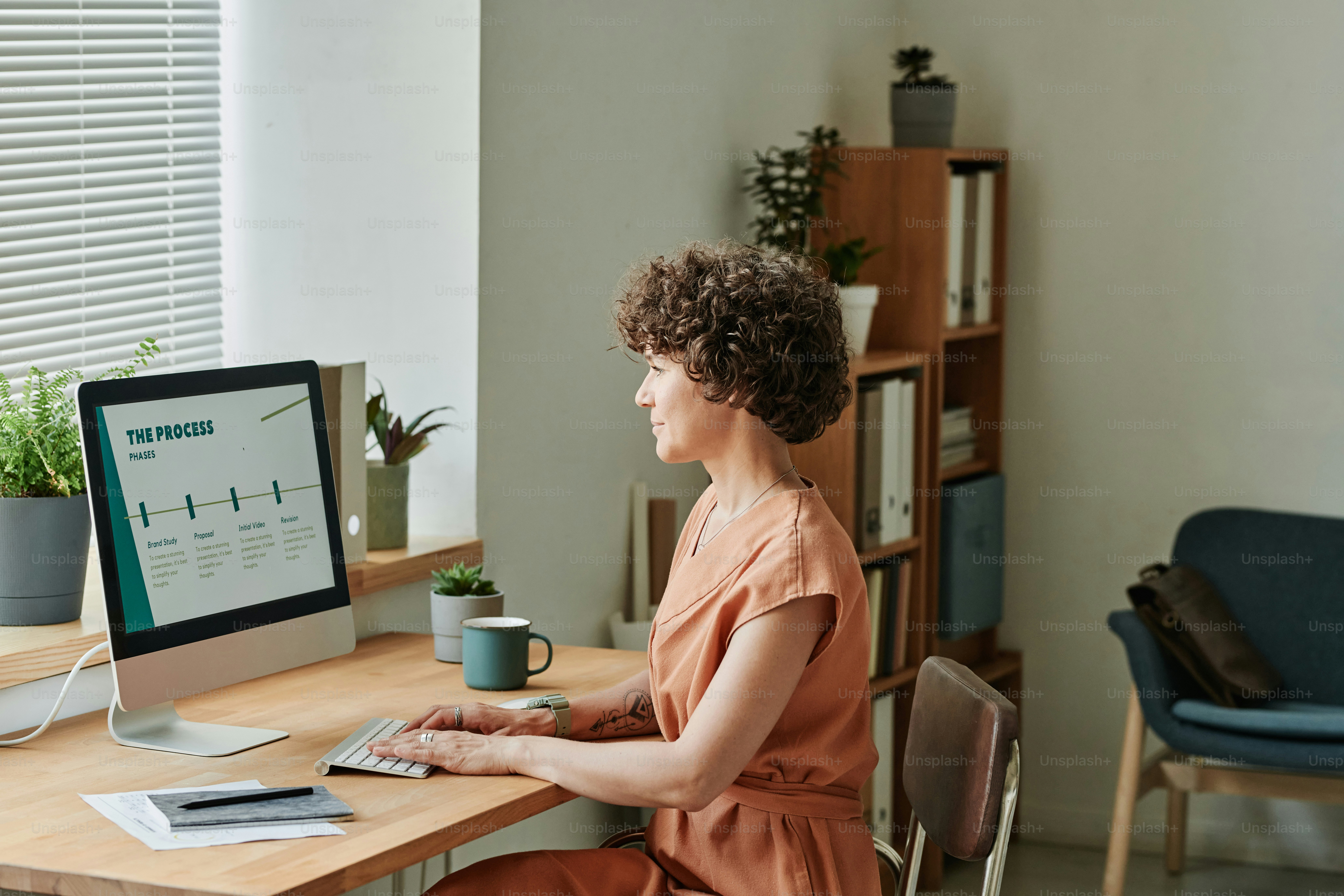 Young businesswoman sitting at table in front of computer monitor and working online at modern office