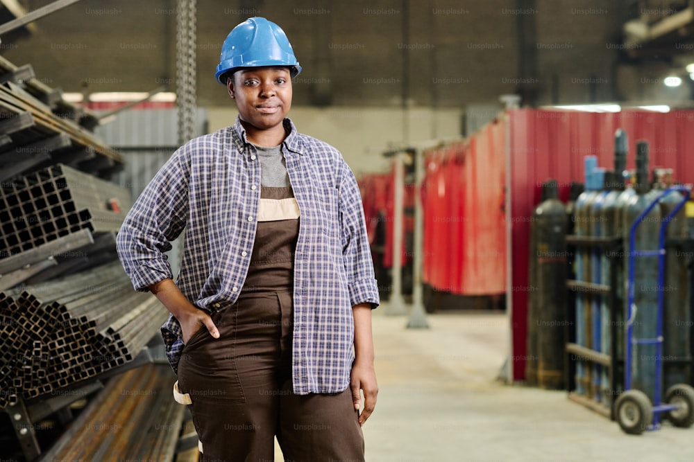 Portrait d’un ouvrier professionnel africain de l’industrie lourde en casque debout dans l’atelier d’usine