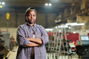 Portrait of female worker posing confidently while standing with arms crossed in factory workshop