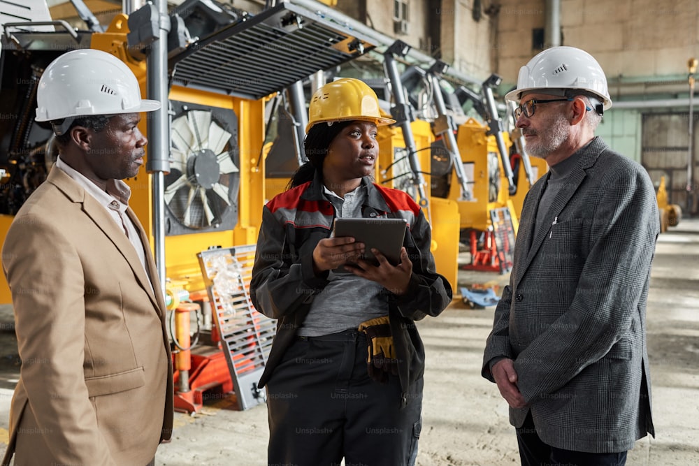 African female foreman using digital tablet in her work during her meeting with engineers in factory