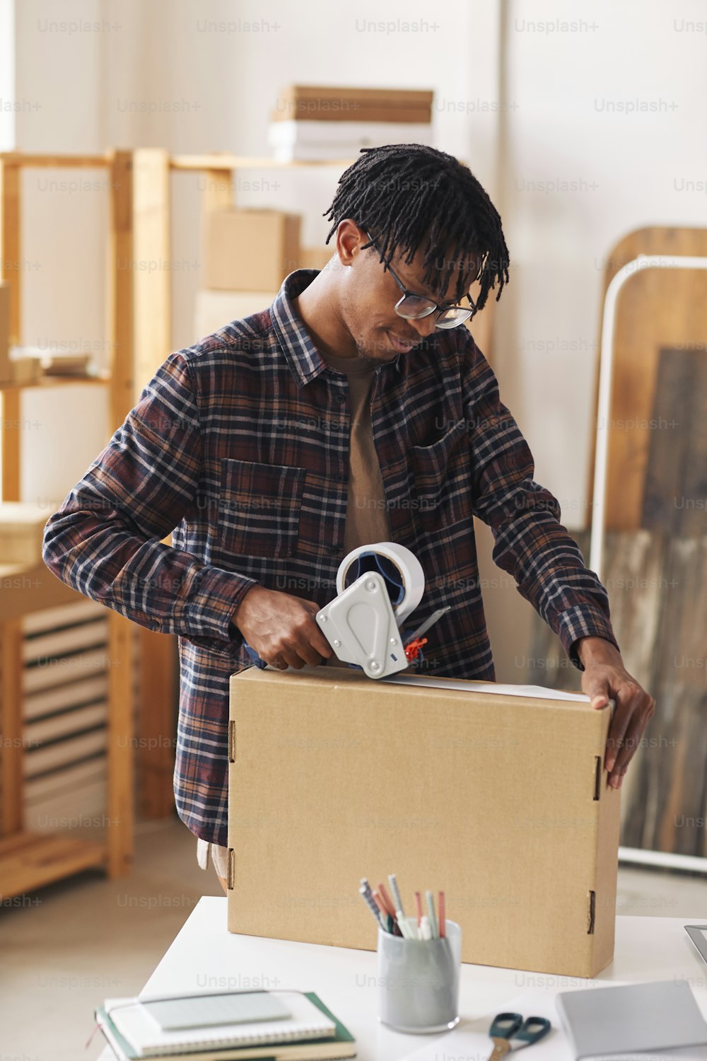 African man closing box with adhesive tape he preparing parcels for delivery