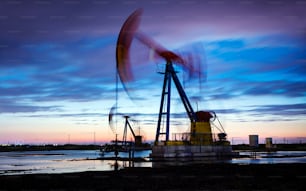 Oil field site, in the evening, oil pumps are running