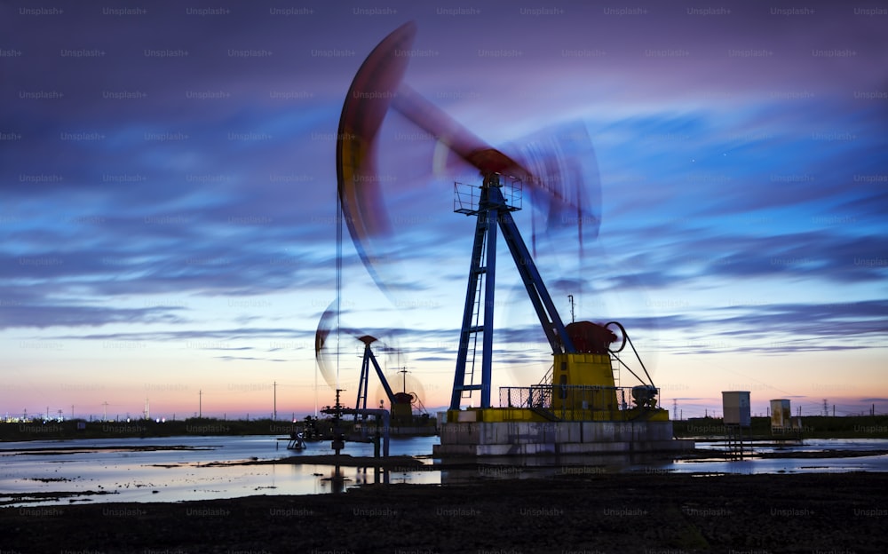 Oil field site, in the evening, oil pumps are running