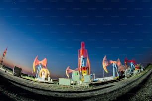 Oil field site, in the evening, oil pumps are running