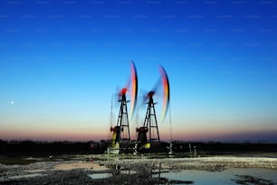 Oil field site, in the evening, oil pumps are running