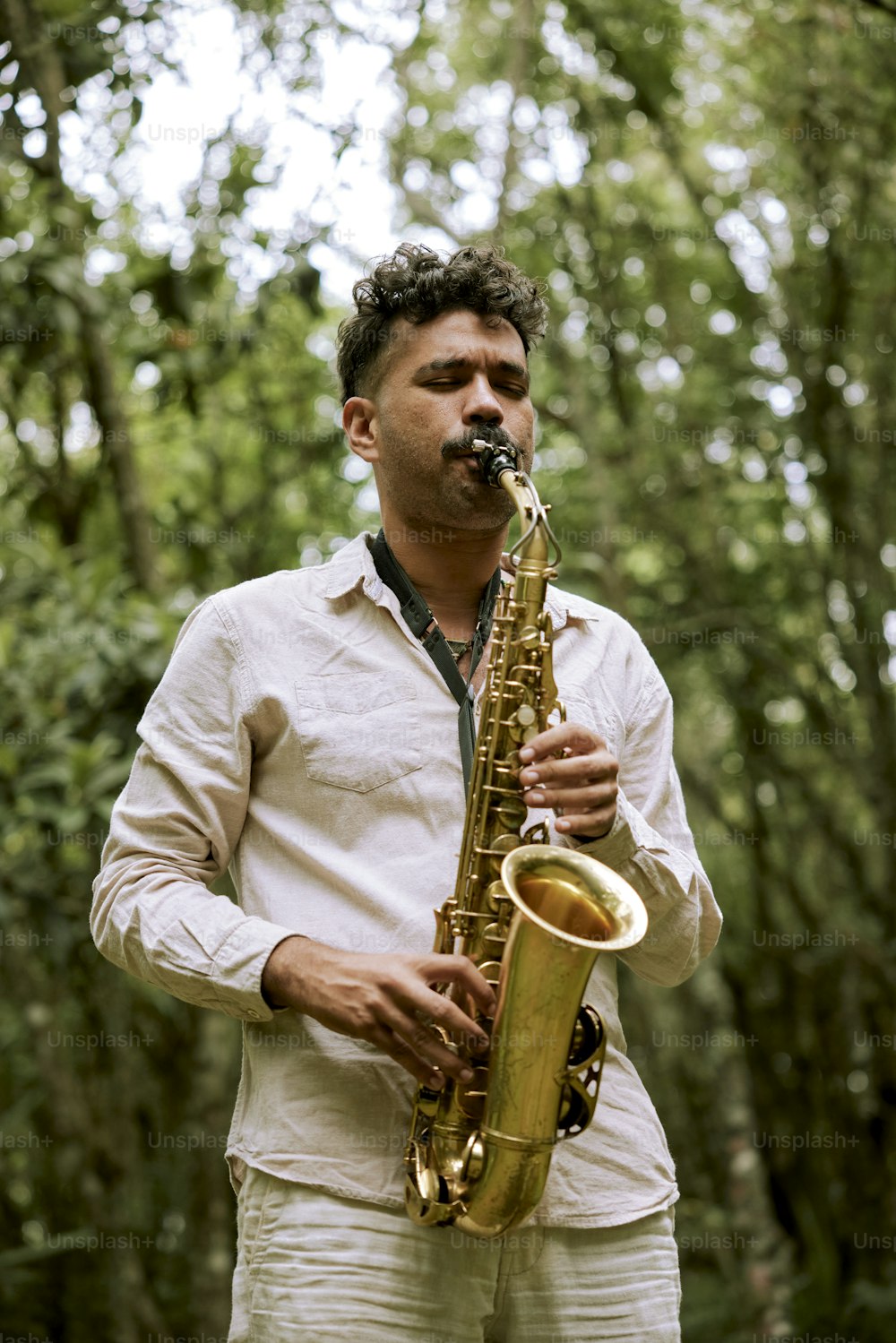 a man playing a saxophone in a forest