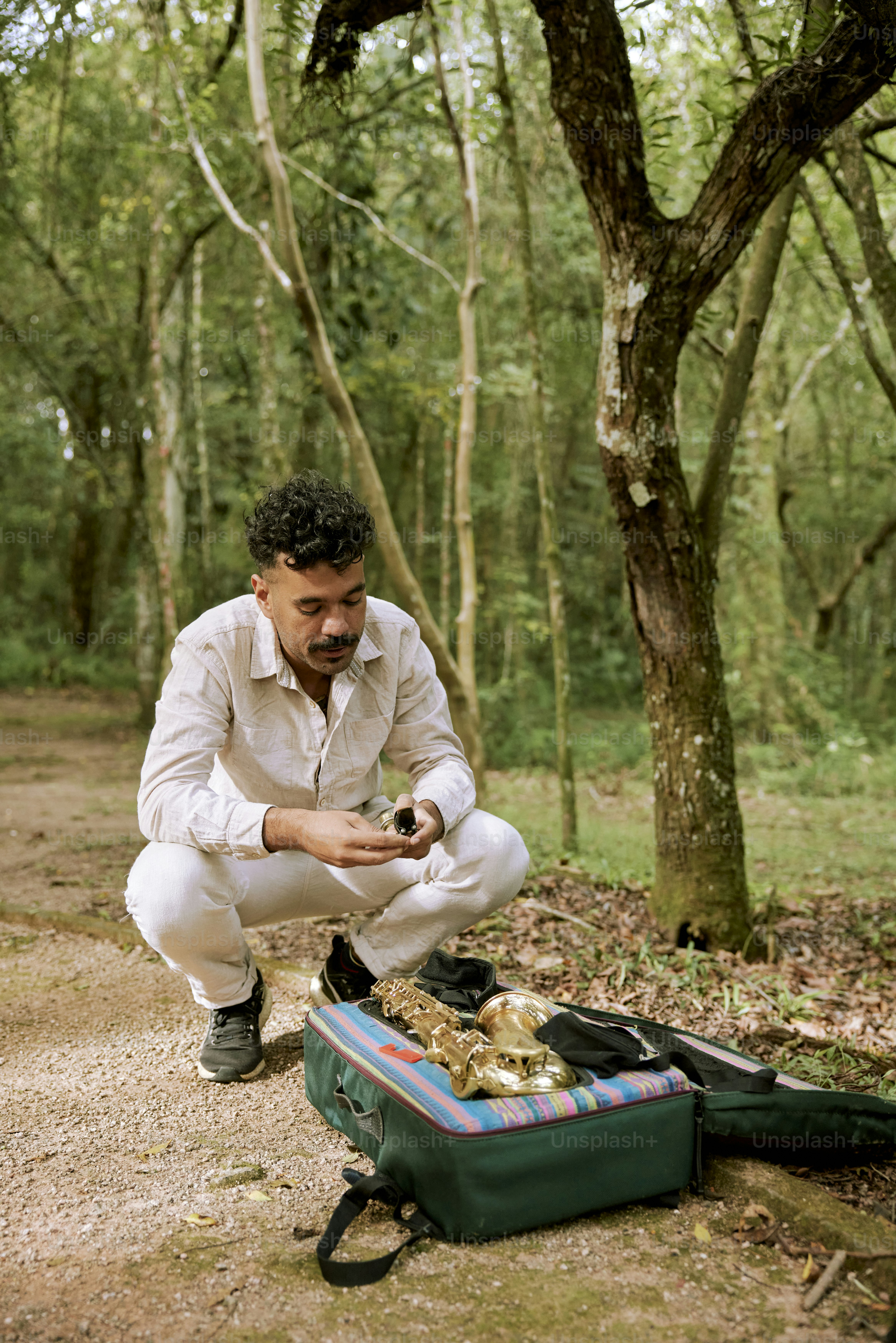 a man kneeling down next to a green suitcase