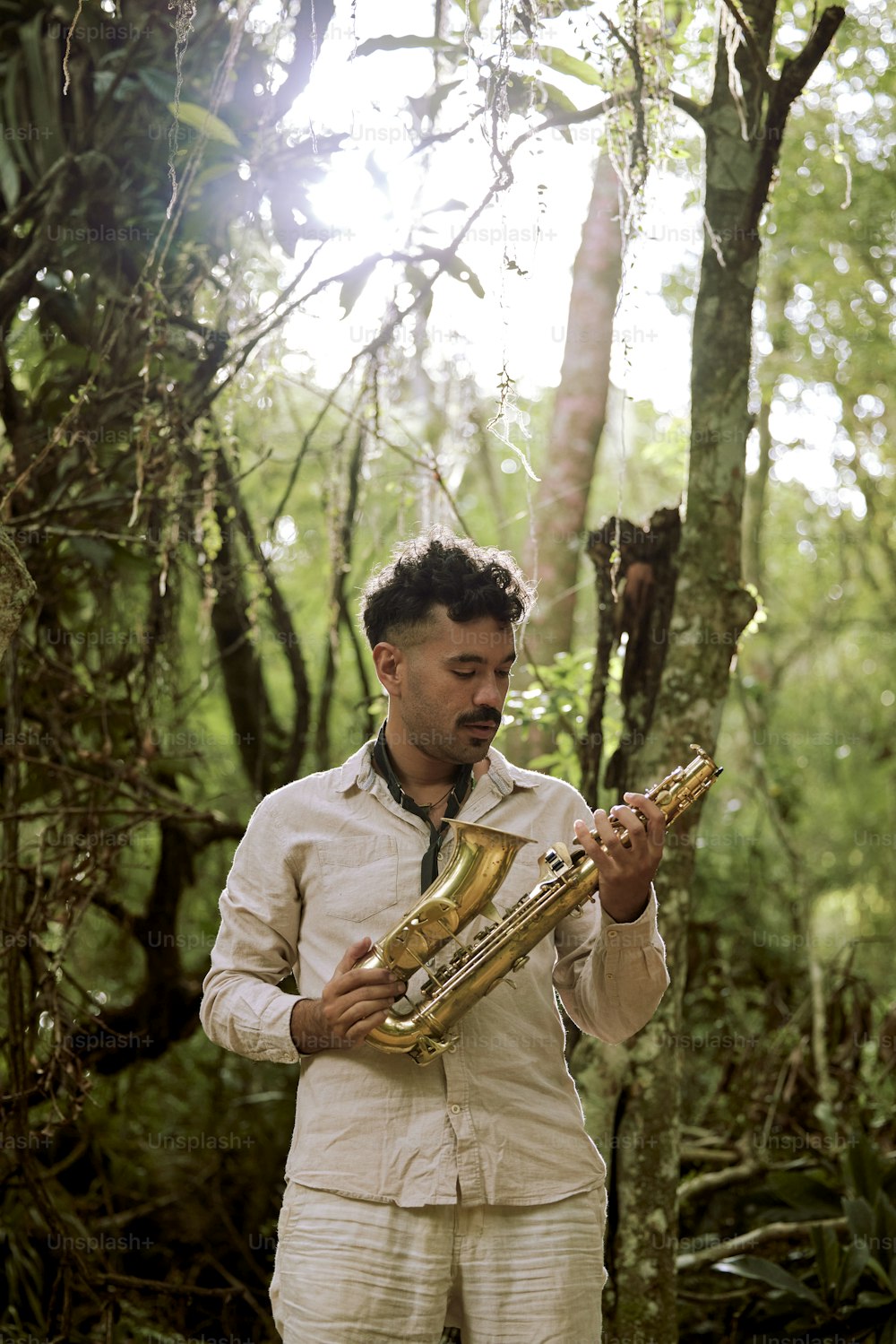 a man standing in a forest holding a saxophone