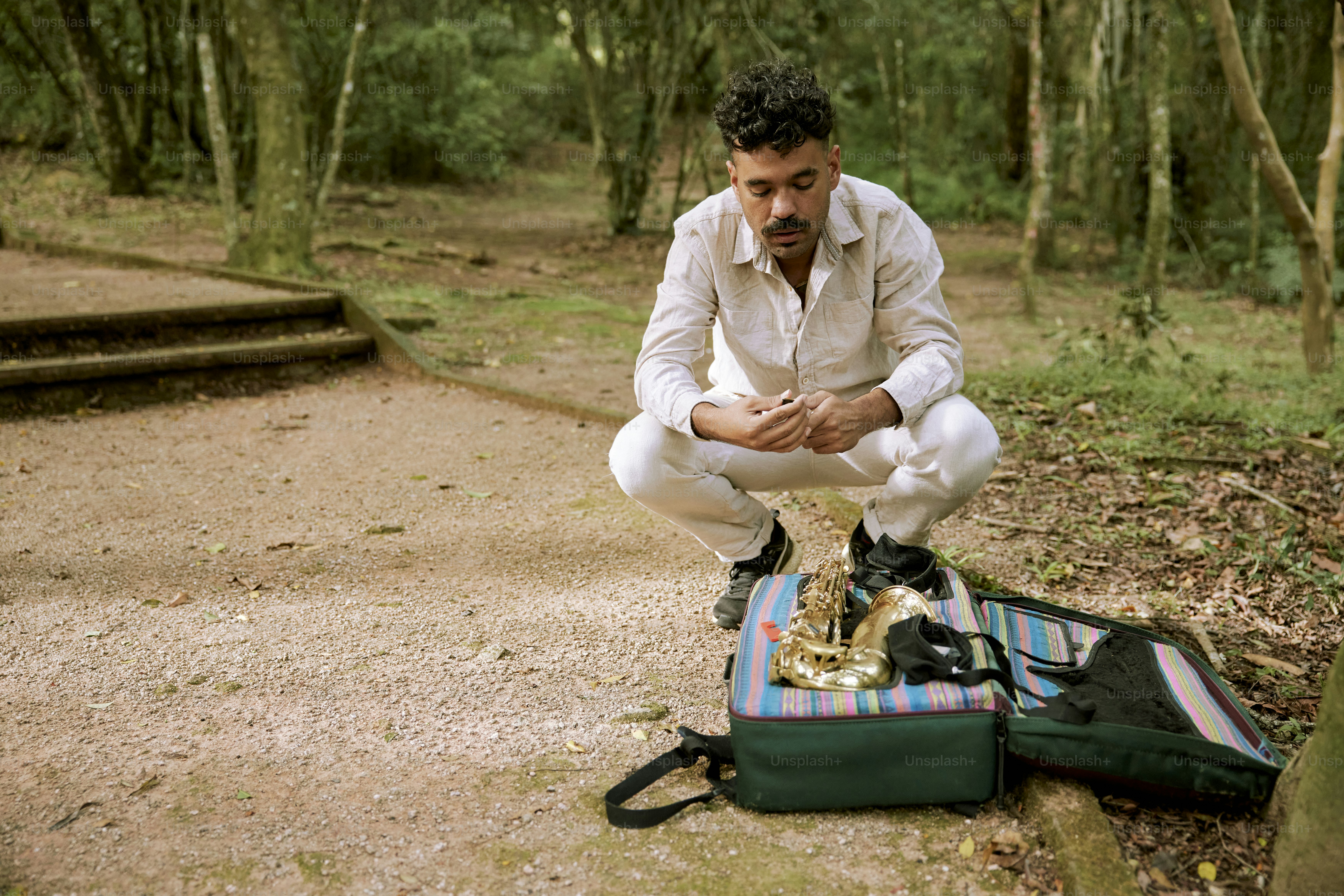 a man sitting on a suitcase in the woods