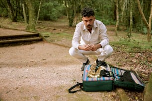 a man sitting on a suitcase in the woods