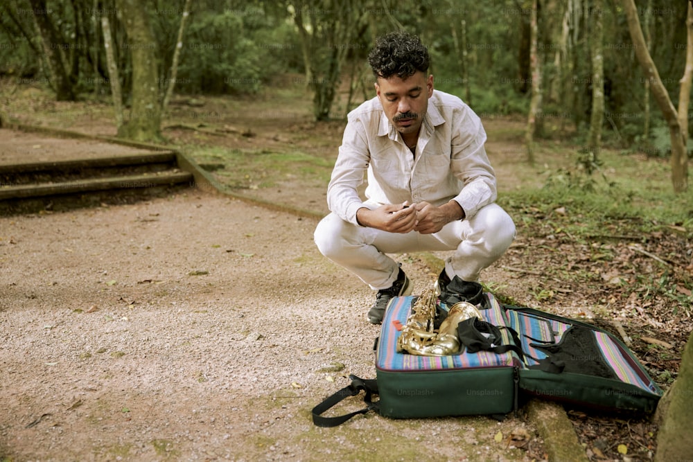 Un uomo seduto su una valigia nel bosco