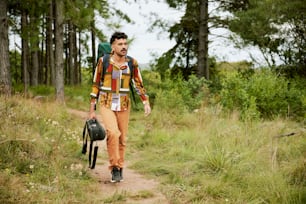 a man walking down a dirt road with a backpack