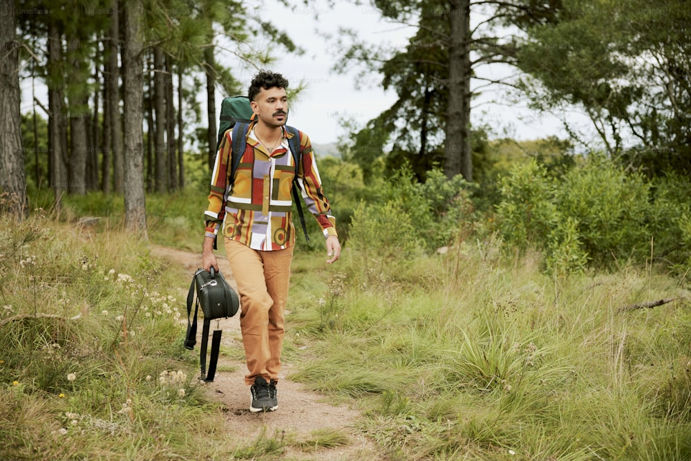 um homem andando por uma estrada de terra com uma mochila