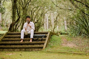 a man sitting on a set of steps in the woods
