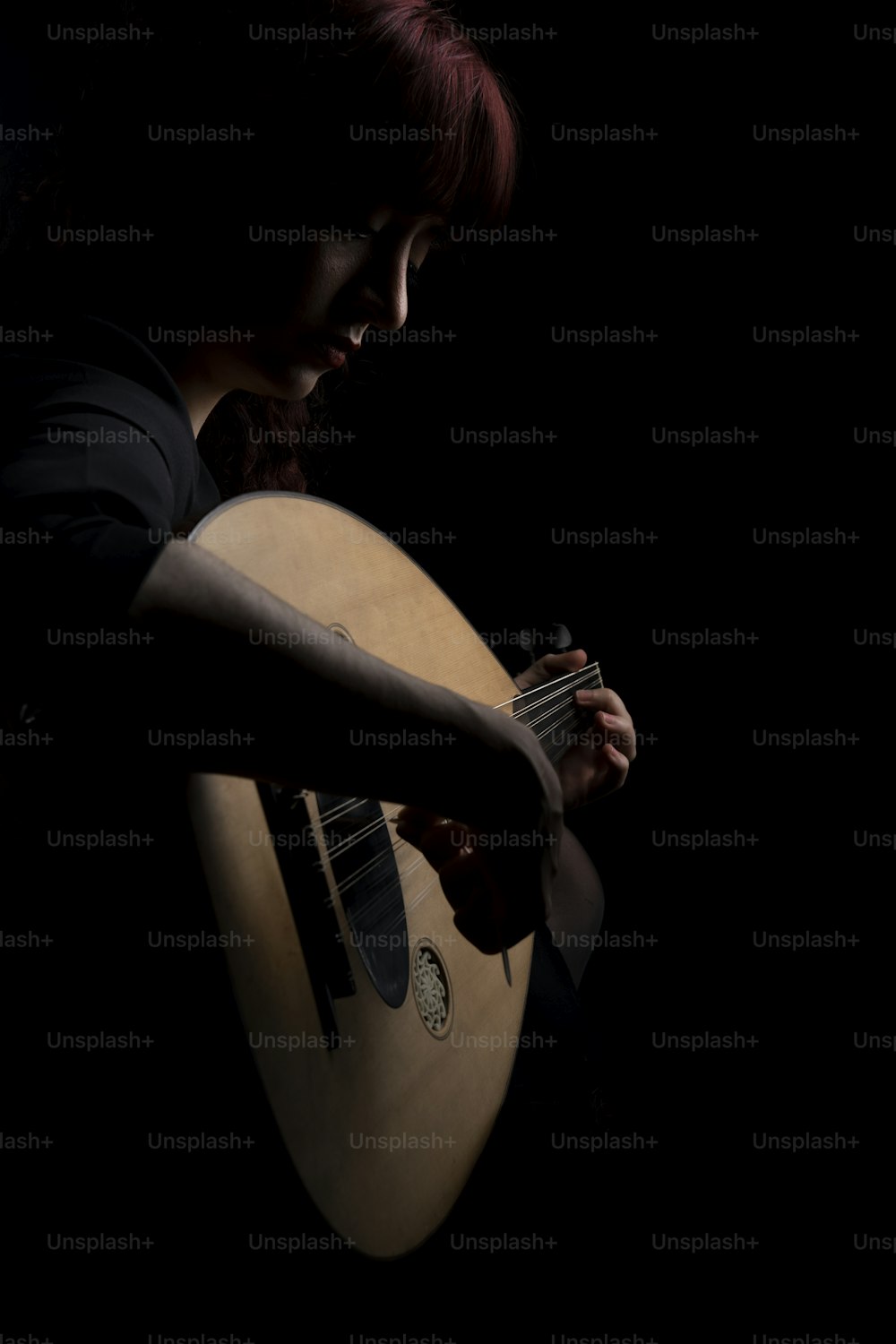 Una mujer sosteniendo una guitarra en la oscuridad
