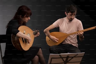 a man and a woman are playing guitars