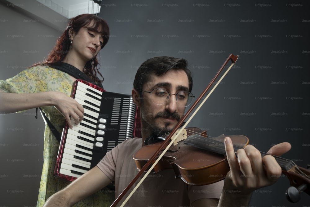 un hombre tocando un violín y una mujer tocando un acordeón