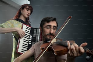 un hombre tocando un violín y una mujer tocando un acordeón