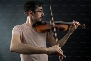 Un hombre tocando un violín sobre un fondo negro