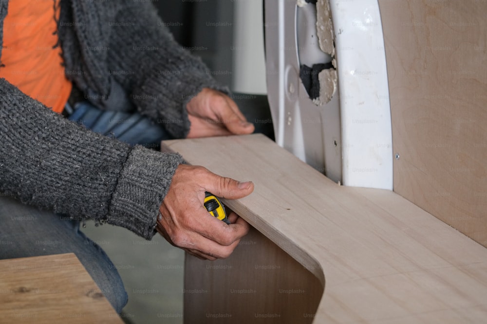 a man is using a screwdriver on a piece of wood