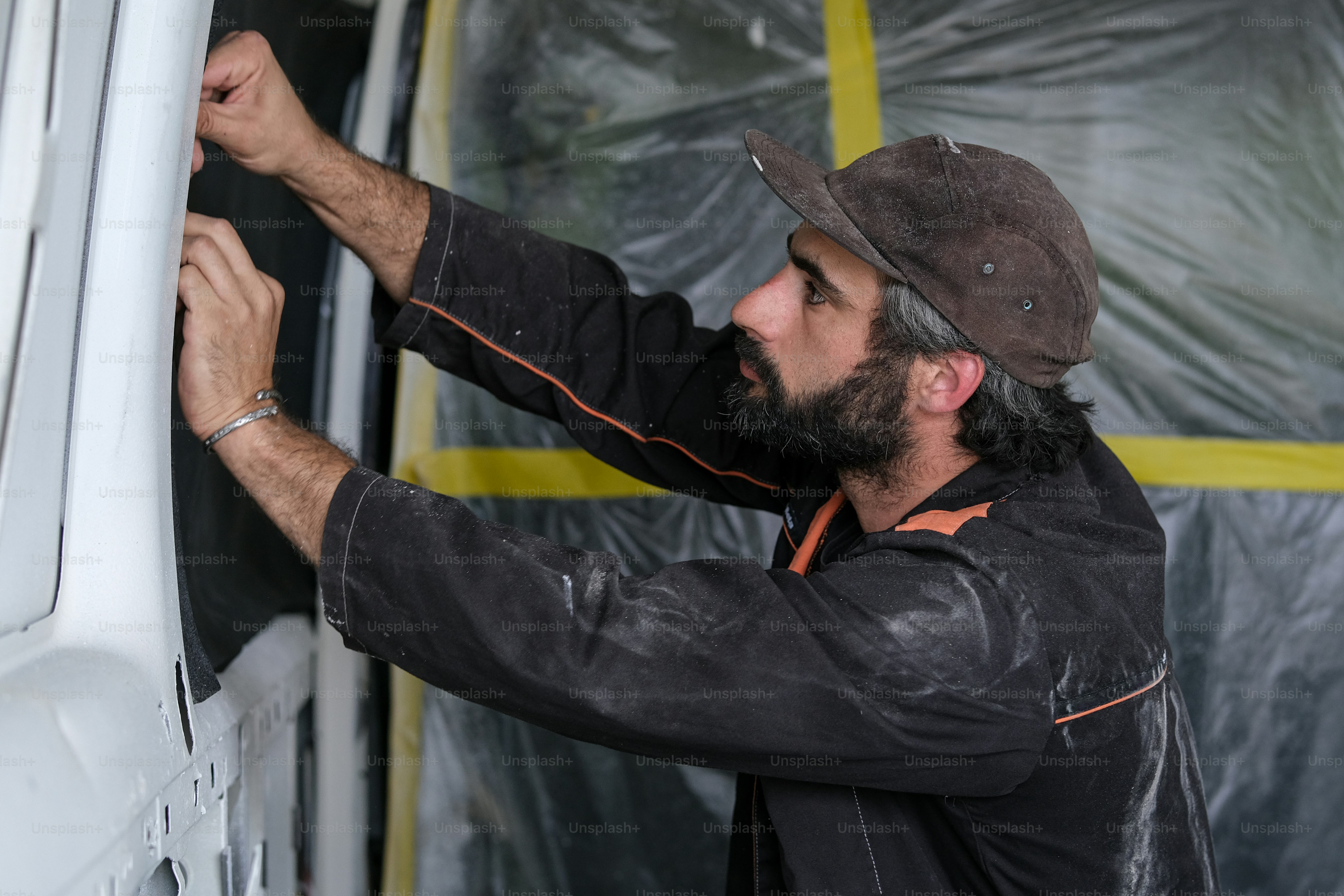 a man in a hat is painting the side of a van