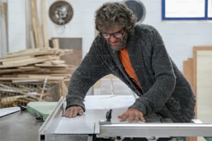 a man working on a table sawing a piece of wood
