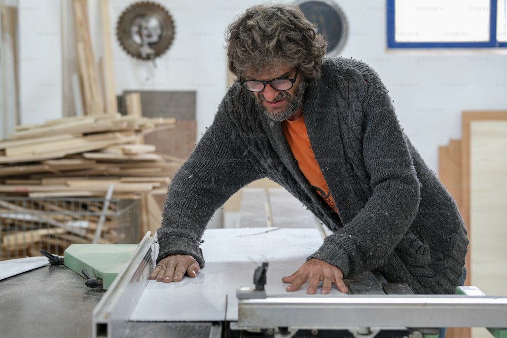 Ein Mann, der an einem Tisch arbeitet und ein Stück Holz sägt