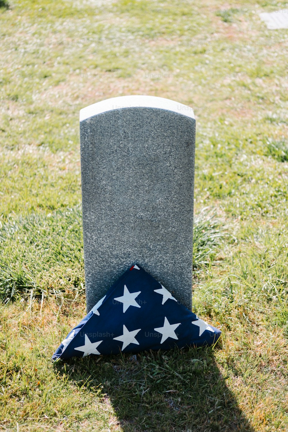 uma bandeira deitada no chão ao lado de uma sepultura