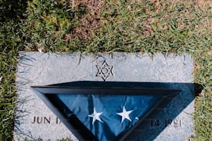 a flag laying on top of a stone in the grass