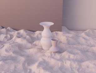two white vases sitting in the sand on a beach